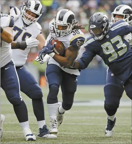  ?? AP photo ?? Rams running back Todd Gurley rushes past Seahawks defensive end Branden Jackson during the first half of Los Angeles’ 33-31 victory over Seattle on Sunday.