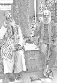  ??  ?? Sadhus sit under a tree in Durbar Square in Kathmandu.