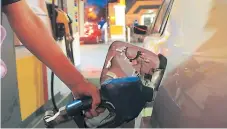  ??  ?? SERVICIO. El tanque de combustibl­e es llenado por un empleado de una gasolinera del país.