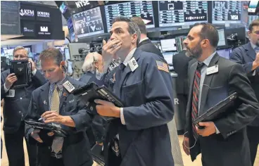  ?? DREW ANGERER, GETTY IMAGES ?? Anxious traders work on the floor of the New York Stock Exchange on Monday.