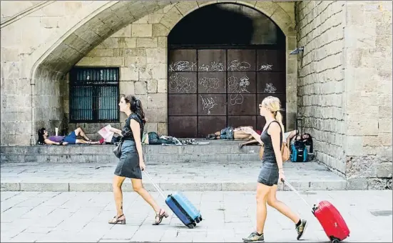  ?? XAVIER CERVERA ?? Imagen de la zona de los Jardins Rubió i Lluch, en el Raval, con dos turistas y al fondo personas que duermen en la calle