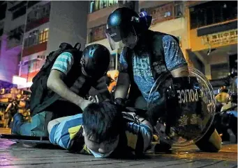 ?? AP ?? Hong Kong policemen arrest a protester during a faceoff outside a police station in Sham Shui Po district yesterday. China has promised that it will eventually punish those behind two months of protests.