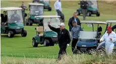  ??  ?? Donald Trump is surrounded by a posse of golf-buggy-propelled Secret Service agents during a game at his Turnberry course in Scotland. GETTY IMAGES