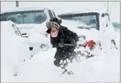  ?? ROBERT F. BUKATY/AP ?? A woman shovels around her car Thursday in Portland, Maine. Forecaster­s tracked another possible storm.