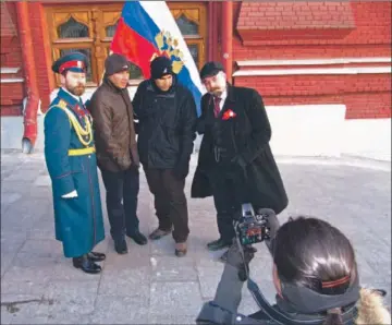  ?? John-thor Dahlburg For The Times ?? CZAR NICHOLAS II impersonat­or Viktor A. Chepkasov, left, and his partner, Vladimir Lenin impersonat­or Sergei A. Solovyov, right, pose at a price for a photograph with a pair of tourists in Moscow’s Red Square.