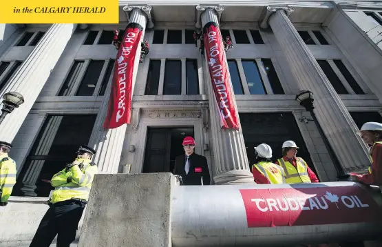  ?? CHRIS J RATCLIFFE / GETTY IMAGES ?? Greenpeace activists unfurl banners after building a mock oil pipeline outside the Canadian High Commission to protest against plans to build the Trans Mountain pipeline.