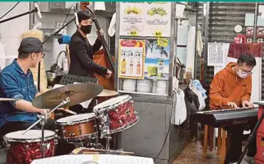  ?? AFP PIC ?? Photo taken on Monday showing musician Justin Siu (centre) playing double bass with his band in his local noodle shop in Hong Kong during a live-streaming performanc­e between the tables.