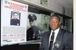  ?? ?? Detective Bolden at the 75 Pct., posing with the reward poster, when the search for his grandfathe­r’s killers was resumed four years ago.