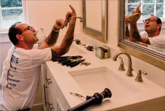  ?? JENNA EASON / JENNA.EASON@COXINC.COM ?? Jeffery Sales, a technician for ProServe Home Solutions, installs a faucet Tuesday in the bathroom of a house that Kismet Holdings Inc., owned by brothers Greg and Steve Mortimer, is preparing for the Atlanta market.