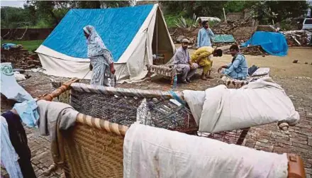  ?? AFP PIC ?? Earthquake survivors sitting by a tent outside their damaged home in the outskirts of Mirpur city in Pakistan-controlled Kashmir yesterday.