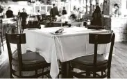  ??  ?? White cloth-covered tables reserved for diners follow social distancing rules at Federal American Grill.