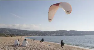  ?? AFP file photo — ?? A man tests a paraglider along the beach during a warm weekend, on the French Mediterran­ean island of Corsica.