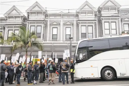  ?? Photos by Jessica Christian / The Chronicle ?? Members of the Teamsters Union carry signs as they block a shuttle bus at 18th and Castro streets in San Francisco.