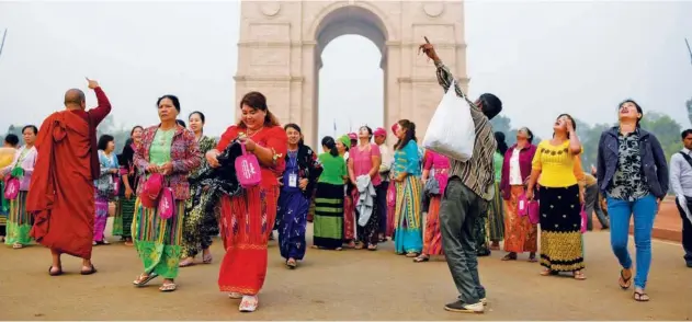  ?? Associated Press ?? A street vendor selling projectile toys around the India Gate monument tries to attract a group of tourists from Myanmar in New Delhi on Tuesday.