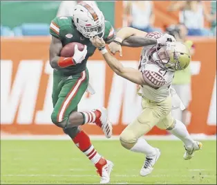  ?? David Santiago / Miami Herald via AP ?? Florida State punter Logan Tyler grabs Miami wide receiver Jeff Thomas by the mask while trying to tackle him Saturday. Thomas had three catches for 76 yards.