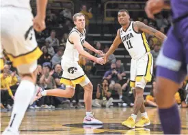  ?? JULIA HANSEN/IOWA CITY PRESS-CITIZEN ?? Iowa’s Payton Sandfort (20) and Tony Perkins (11) high-five while playing Kansas State in a first-round NIT game on Tuesday at Carver-Hawkeye Arena in Iowa City, Iowa.