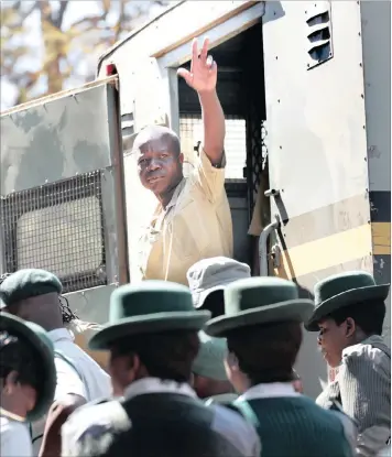  ?? PICTURE: AARON UFUMELI / EPA ?? NO GOING BACK: Freelance videograph­er James Jemwa raises a victory sign in a prison vehicle amid police and prison officials at the Harare Magistrate’s Court. At least 67 anti-government protesters who were arrested last week during a protest for...