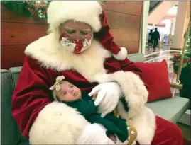  ?? HAVEN DALEY / AP ?? A Santa holds a baby Monday at Stonestown Galleria in San Francisco. Santa is back this year, but he pleads diligence as he continues to tiptoe through the pandemic. Amid a downturn in available Santas, about 15 percent fewer in one large database, some are busier than ever.