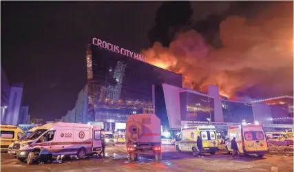  ?? MAXIM SHEMETOV, REUTERS ?? Vehicles of Russian emergency services are parked near the burning Crocus City Hall concert venue following the terrorist attack orchestrat­ed by ISIS-K.