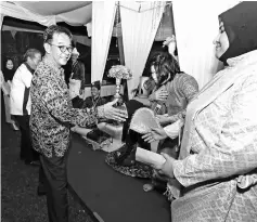  ??  ?? Abdul Karim greets the exhibitors at a Malay booth – one of many at the festival ground.