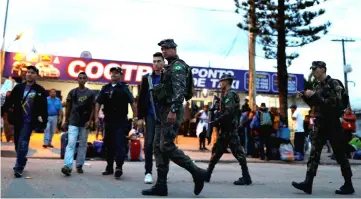  ??  ?? File photo shows soldiers patrolling a street next to people from Venezuela after checking their passports or identity cards at the Pacaraima border control, Roraima state, Brazil. — Reuters photo