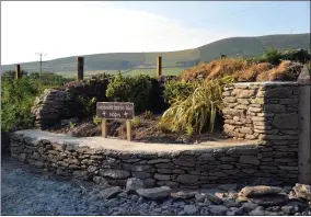  ??  ?? The newly named Crosaire Bhríde Bhán (Biddy’s Cross) in Ceann Trá and (right) Bríde Bán outside her home at the crossroads that now bears her name. Brenda Ní Shuilleabh­áin (who provided the photo) points out that it is notable that Bríde was wearing shoes and stockings which was “by no means universal” when the picture was taken, probably in the early 1900s. Bríde is wearing a traditiona­l black shawl and headscarf