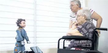  ?? MICHELLE SIU/THE CANADIAN PRESS ?? Elizabeth Graner, who has dementia, sits in her wheelchair as her daughter Penny Blake helps her interact with Ludwig, a two-foot-tall robot created by University of Toronto researcher­s to engage people with Alzheimer’s disease and dementia, at a press...