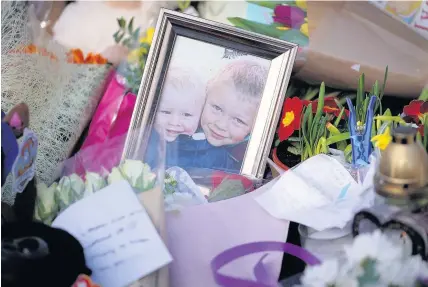  ?? Christophe­r Furlong ?? > A photograph of Casper and Corey Platt-May, aged two and six, sits among floral tributes to the two brothers who died after a suspected hit-and-run in Coventry