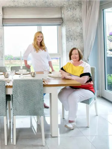  ??  ?? TOP LEFT: Cora and Bill Kee, under Lorna’s guidance, opted for highgloss units with minimal handles. The units were made by Peter McAuleyABO­VE: Interior architect Lorna Kee and her mother in Cora’s new light-filled dining area. The back is north-facing but still gets a lot of sun as the house is a bungalow. The tiles are porcelain, the wallpaper is by Harlequin and the geometric-patterned fabric on the chairs is by RomoTOP RIGHT: The metro tiles in the en suite bathroom are a nice feature. “Tilers don’t love them as they involve more cutting and grouting,” Lorna notesRIGHT: Bill and Cora embraced the notion of a modern house, but Bill did want his antique armchair as a memento of Iona. “Daddy’s throne,” Lorna calls it