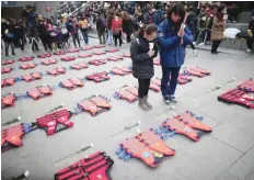  ?? — Reuters ?? A mother prays with her daughter in front of life vests symbolisin­g the 304 victims of sunken ferry Sewol.