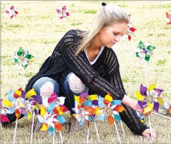  ?? Photo by Randy Moll ?? Kylie Bennett, a Gentry sophomore, places pinwheels on the lawn at Gentry Police Station on Friday. A total of 439 pinwheels were placed by the Gentry High School student council and police, representi­ng the 439 cases of confirmed child abuse in Benton...
