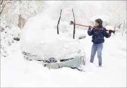  ?? Kristin Murphy / The Deseret News photo via AP ?? Cathy Morgan-Mace cleans snow and ice off her family’s car during a snowstorm in Salt Lake City, Utah on Wednesday. A brutal winter storm knocked out power in California, closed interstate highways from Arizona to Wyoming and prompted more than 1,200 flight cancellati­ons Wednesday — and the worst won’t be over for several days.