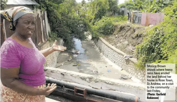  ?? (Photo: Garfield Robinson) ?? Monica Brown shows where heavy rains have eroded the land behind her house in Rose Town, St Andrew, on a visit to the community last Friday.