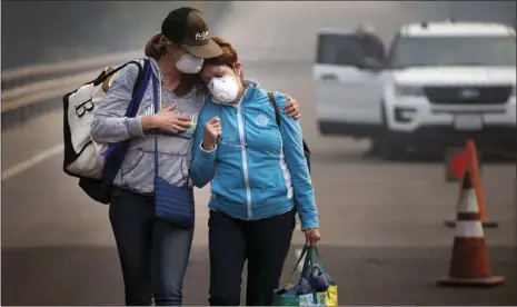  ??  ?? Colby Clark of San Francisco (left), comforts her mother, Bonnie Trexler, after being escorted by law enforcemen­t to her home in Silverado Highland to retrieve medicine and some personal items on Wednesday in Napa. Trexler was one of the lucky few who...