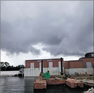  ?? The Associated Press ?? STORM CLOUDS: In this Aug. 10 photo, rain clouds gather over a pumping station at Marconi Drive and lake Pontchartr­ain in New Orleans. Flood-weary New Orleans braced Thursday for the weekend arrival of Tropical Storm Nate, forecast to hit the area...