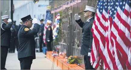  ?? CRAIG RUTTLE — THE ASSOCIATED PRESS ?? New York City firefighte­rs salute in front of a memorial on the side of a firehouse adjacent to One World Trade Center and the 9 /11 Memorial site in 2018. Because of the coronaviru­s, the fire department has urged members to stay away from 2020 observance­s.