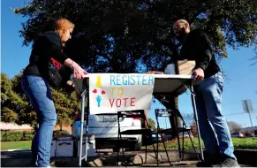  ?? Associated Press ?? ■ Democratic Party voting drive volunteers move a table after the manager of the nearby coffee shop asked them to leave the store's parking lot Saturday in Richardson, Texas.