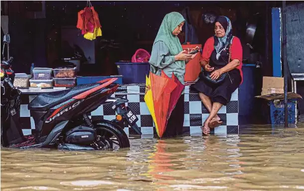  ?? ?? PENIAGA nasi lemak di Padang Jawa, Shah Alam menunggu pelanggan dalam banjir, semalam. - Gambar NSTP/AHMAD UKASYAH
