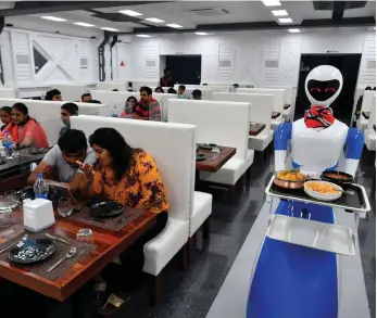  ?? AFP ?? A robot waiter at a cafe in India. AI is increasing­ly being used across industries in the country