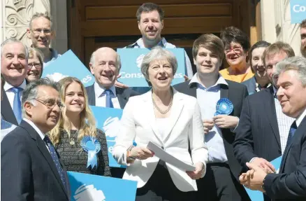  ??  ?? Prime Minister Theresa May (C) flanked by supporters poses outside Wandsworth Town hall in London following local elections on Friday. — AFP