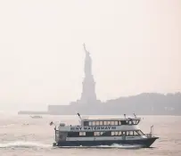  ?? Spencer Platt / Getty Images ?? The Statue of Liberty stands behind a cloud of haze in New York City. Wildfire smoke from the West has arrived in the tristate area, creating decreased visibility and a yellowish haze in many areas.