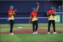  ?? THE CANADIAN PRESS COLE BURSTON ?? Canadian cricket team captain Saad Bin Zafar waves as he’s flanked by teammates Nicholas Kirton, left, and Jeremy Gordon, right, after throwing out the first pitch at the Toronto Blue Jays game against the Minnesota Twins in Toronto on Friday.