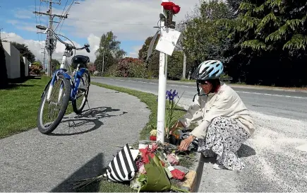  ??  ?? Motueka resident Jennifer Simons places flowers at a memorial to Thomas Armit at the scene of his fatal motorbike crash.