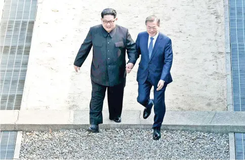  ??  ?? Kim (left) walks with Moon Jae-in over the Military Demarcatio­n Line that divides their countries as they meet at Panmunjom. — AFP photo