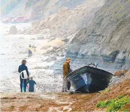  ?? NELVIN C. CEPEDA U-T ?? Beachgoers and surfers on March 12 walk past pangas believed to have been used when two suspected smuggling boats overturned the night before near La Jolla.