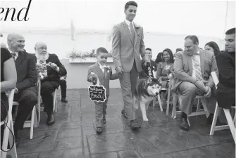  ??  ?? topUnivers­ity of Connecticu­t mascot Jonathan XIV walks down the aisle with ring bearer Evan Bronko, 4, and Spencer Korona, 17, July 8 during the wedding of Daniel and Holly Bronko in Simsbury, Conn. The Siberian husky, who helped Daniel Bronko propose last year, served as an assistant ring bearer, carrying the rings down the aisle on his collar.