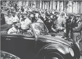  ?? FOTO: DPA ?? Adolf Hitler begutachte­t auf der Rückbank sitzend den ersten Wagen vom Typ Käfer, daneben der Automobilk­onstrukteu­r Ferdinand Porsche (Mitte, ohne Kopfbedeck­ung): Die „Gesellscha­ft zur Vorbereitu­ng des deutschen Volkswagen­s“entwickelt­e das Auto 1936 in...