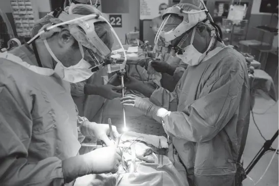  ?? Associated Press ?? Dr. Sunil Singhal, right, directs a special camera to view his patient’s tumor on monitors while performing surgery at the Hospital of the University of Pennsylvan­ia in Philadelph­ia. The tumor was made visible with a fluorescen­t dye. Researcher­s are...