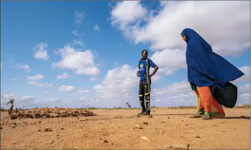  ?? (AP/Jerome Delay) ?? Fartum Issack (right) and her husband, Adan, stand by the grave of their 1-year-old daughter Sept. 19 at a displaceme­nt camp on the outskirts of Dollow, Somalia. The graveyard opened in April, and there’s easily room for hundreds more graves.