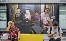  ?? - Reuters ?? AIMED AT CURBING DISSENT: Commuters sit in front of an advertisem­ent discouragi­ng the disseminat­ion of fake news, at a train station in Kuala Lumpur, Malaysia March 28, 2018.